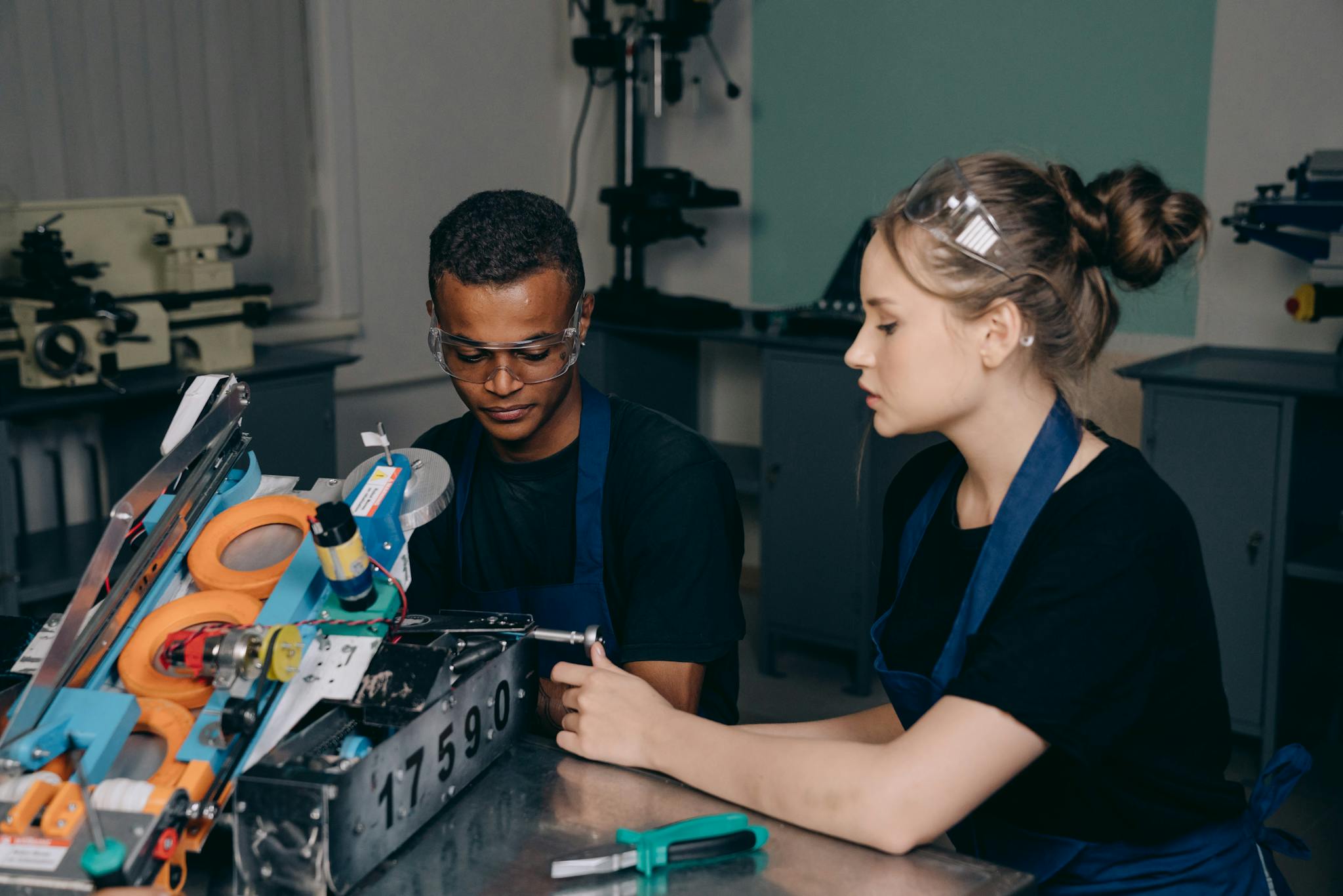 Young engineers working on a robot project in a workshop setting.