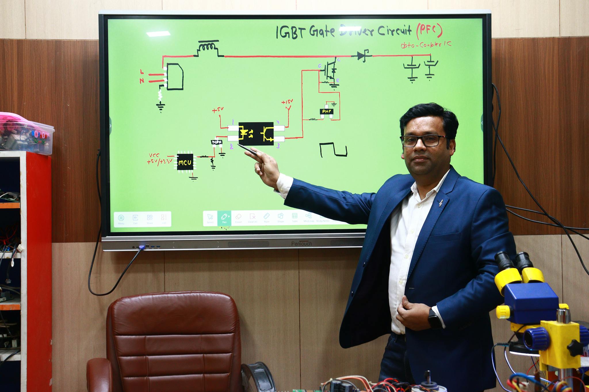 Engineer explains IGBT gate driver circuit on interactive board in classroom setting.
